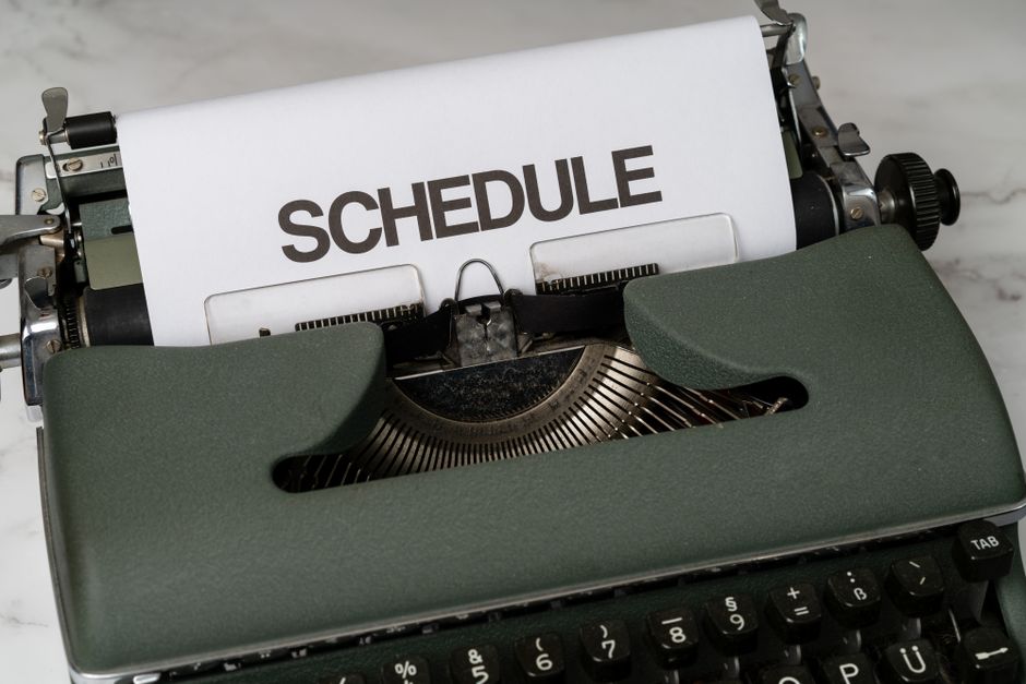 Classic vintage typewriter displaying the word 'SCHEDULE' on paper, resting on a marble surface.